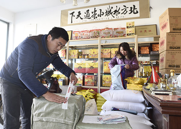 12月3日,“沁州黄小米网店”的店主桂宝强(左)在给客户发货。