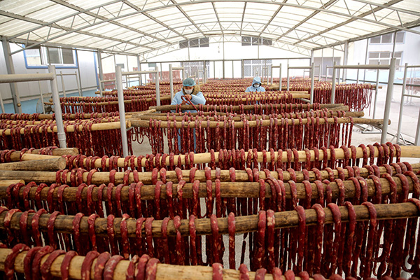 12月19日,江苏睢宁县一食品加工厂的工人在晾晒香肠。