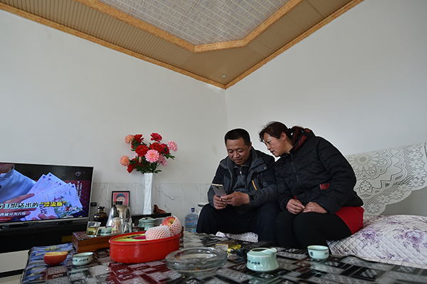 2月21日,宁夏固原市原州区彭堡镇姚磨村村民罗军(左)和妻子马红在自家新盖的房屋内看手机。