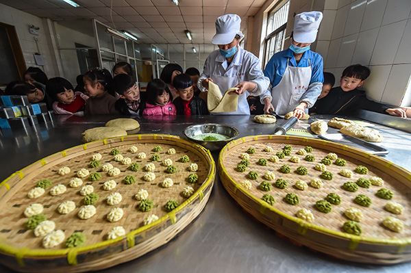 3月21日,塘栖镇卫家埭幼儿园的孩子们在跟随当地传统“老刀糕饼铺”的师傅学做“菜花饼”。