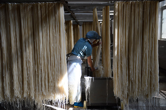 6月18日,工人在江西会昌五丰食品有限公司筛米粉。