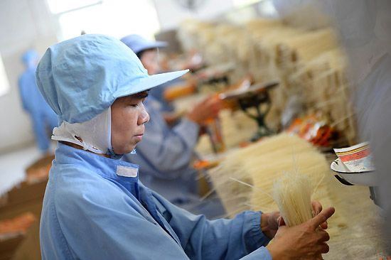 6月18日,工人在江西会昌五丰食品有限公司包装米粉。