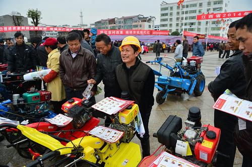3月1日,在高安县农技农机下乡服务现场,一名参观者抬起农机掂量着使用时是否方便。